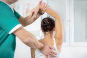 Chiropractor stretching woman's arm behind
